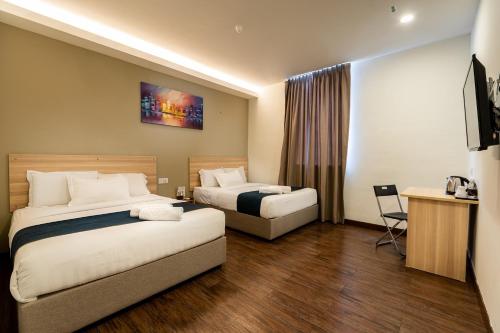 a hotel room with two beds and a desk at 1 Orange Hotel Kuchai Lama KUALA LUMPUR in Kuala Lumpur