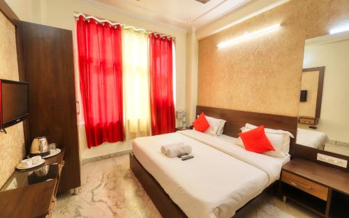 a bedroom with a large bed with red curtains at Hotel Pulse Inn Jaipur in Jaipur