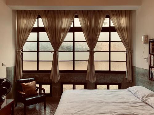1 dormitorio con ventana grande, cama y silla en Shennong 147, en Tainan