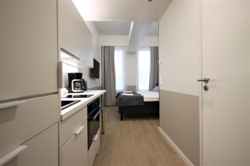 a small white kitchen with a bed in a room at Forenom Aparthotel Varkaus in Varkaus