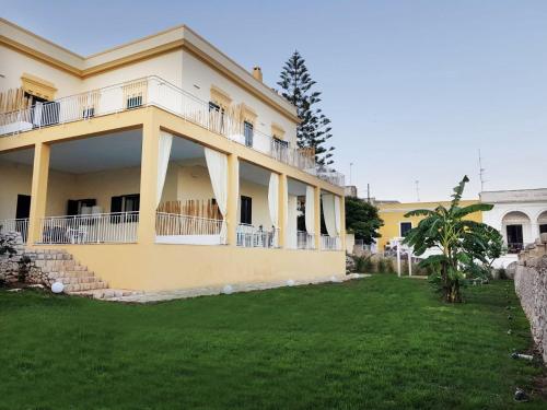 uma grande casa amarela com um quintal em frente em Villa Cesarea Dimora di Charme em Santa Cesarea Terme