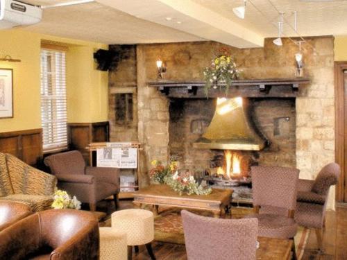 a living room with a fireplace and a couch and chairs at Redesdale Arms Hotel in Moreton in Marsh