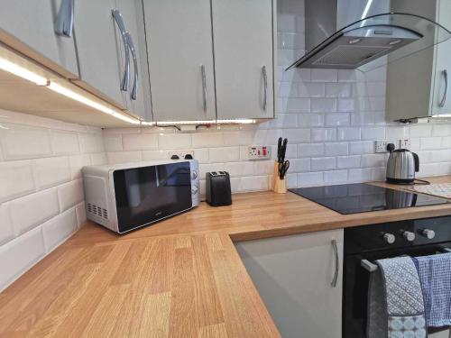a kitchen with a microwave on a wooden counter top at Spacious 4BR Home with Garden, Swansea in Swansea
