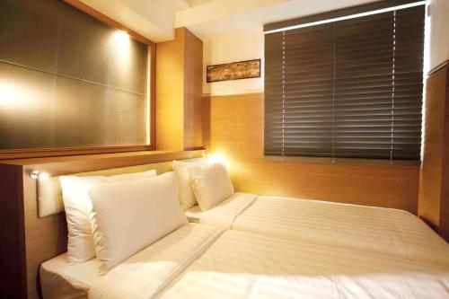 a bedroom with a large white bed with a window at Bluejay Residences in Hong Kong