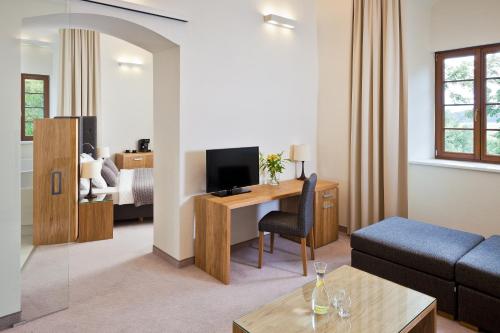 a living room with a couch and a desk with a television at Uroczysko Siedmiu Stawów Spa by L'Occitane in Gola Dzierżoniowska