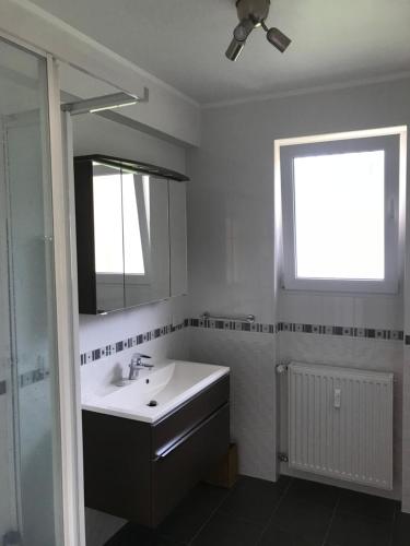 baño con lavabo, espejo y ventana en Waarkstrooss 12, en Welscheid