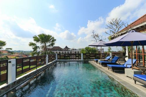 - une piscine avec des chaises et des parasols bleus dans l'établissement Tegal Sari Accommodation Ubud, à Ubud