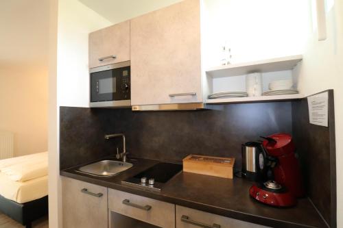 una cocina con fregadero y un aparato rojo en iQ-Hotel, en Langenau