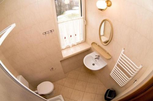 a bathroom with a sink and a toilet and a mirror at Dom Wypoczynkowy Tulipan in Zakopane