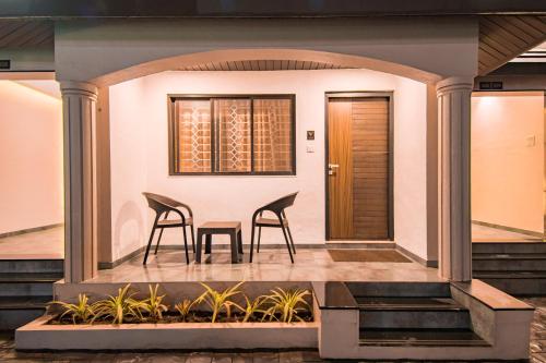 two chairs and a table on the front porch of a house at Treebo Five Elements, Lonavala in Lonavala