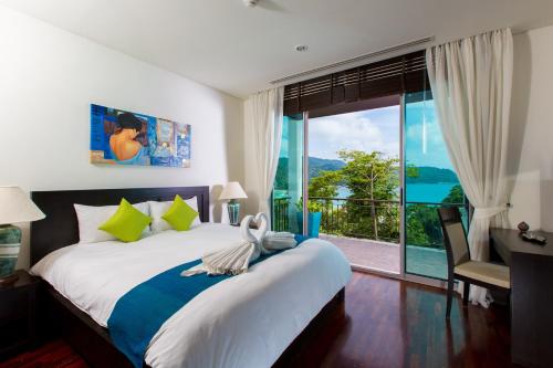 um quarto com uma cama grande e uma janela grande em Kata gardens penthouse seaview with rooftop pool 8C em Praia de Kata