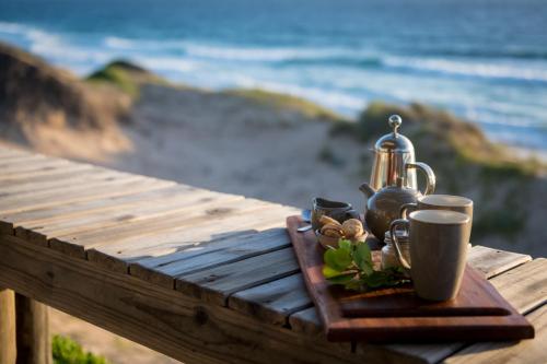 a wooden table with a tray with cups and a tea kettle at Sava Dunes in Miramar
