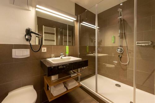 a bathroom with a sink and a shower and a toilet at Hotel Gasthof Krone in Niederstetten