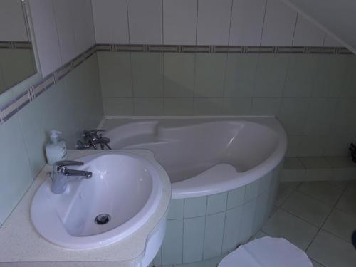 een badkamer met een wastafel en een bad bij Katica Vendégház in Békéscsaba
