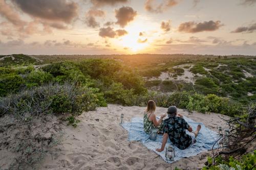 a couple sitting on the beach watching the sunset at Sava Dunes in Miramar