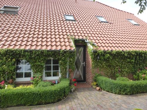 a brick house with a red roof and a door at Friesenwohnung in Norden