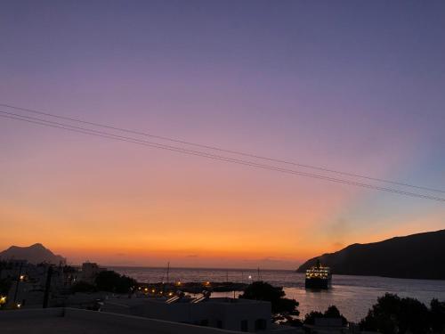 una puesta de sol sobre un cuerpo de agua con un barco en Aelia Studios en Aegiali