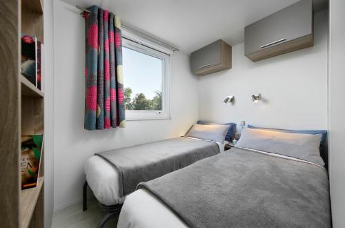 two beds in a room with a window at KNAUS Campingpark Bad Dürkheim in Bad Dürkheim