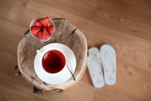 a cup of tea on a wooden table with a bowl of strawberries at MyTime Hotels la Grotta in Vigo di Fassa
