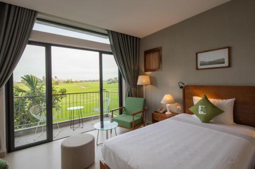 ein Hotelzimmer mit einem Bett und einem Balkon in der Unterkunft Hoian Tranquil Lodge - Chon Binh Yen in Hoi An
