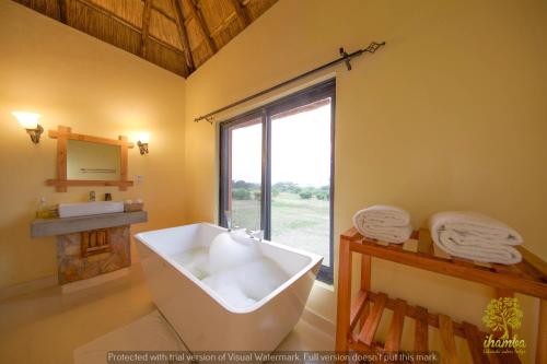 a bathroom with a tub and a sink and a window at Ihamba Lakeside Safari Lodge in Kahendero