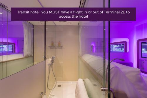 baño con ducha a ras de suelo e iluminación púrpura en YOTELAIR Paris CDG - Transit Hotel - Terminal 2E en Roissy-en-France