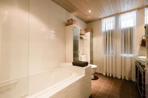 a white bathroom with a tub and a toilet at House in Reykjavik - Birta Rentals in Reykjavík