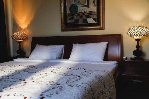 a bedroom with a bed with two lamps on it at Hotel 201 in Podgorica