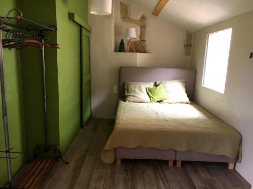 a small bedroom with a bed with green walls at l'Ecurie in Bonnieux