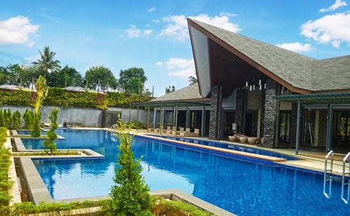 een groot blauw zwembad naast een gebouw bij Vimala Hills Resort Cozy Villa Puncak Gadog Bogor in Bogor
