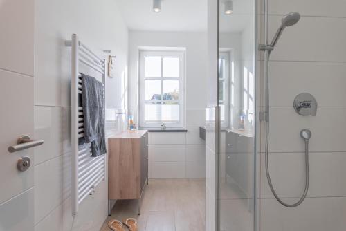 a white bathroom with a shower and a sink at Haus Dünenrose in Börgerende-Rethwisch