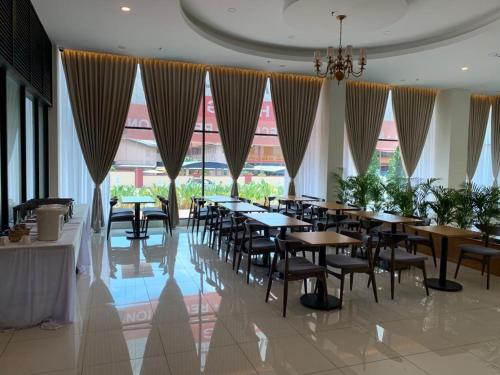 a dining room with tables and chairs and windows at Maple Lodge in Batu Pahat