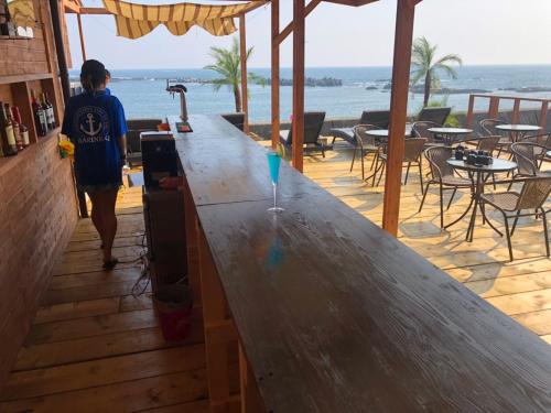 a person walking past a large wooden bar with the ocean at MARINE-Q in Inami