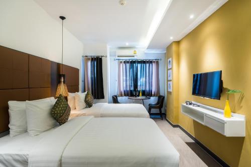 a hotel room with two beds and a flat screen tv at Aim House Bangkok No Parking in Bangkok