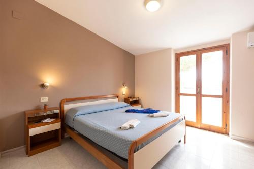 a bedroom with a bed and a window at Hotel La Fattoria Sul Mare in Capo Vaticano
