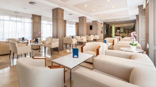 een restaurant met witte banken en tafels en stoelen bij Globales America in Calas de Mallorca