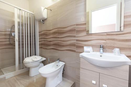 a bathroom with a sink and a toilet and a mirror at Hotel La Fattoria Sul Mare in Capo Vaticano