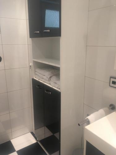 a bathroom with a black cabinet and a tiled wall at Ferienhaus Gumann in Nuremberg