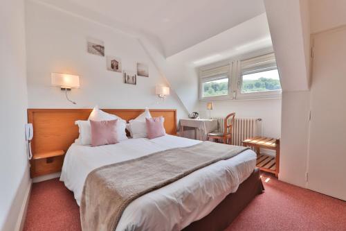 - une chambre avec un grand lit et des oreillers roses dans l'établissement Hôtel Deybach, à Munster