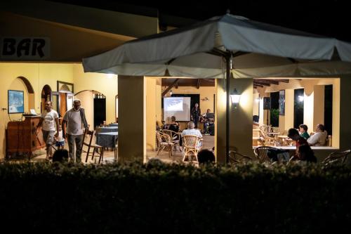 a group of people standing around a patio with an umbrella at Hotel La Fattoria Sul Mare in Capo Vaticano