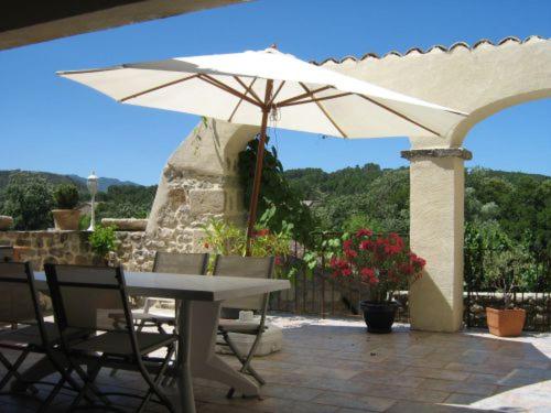 a patio with an umbrella and a table and chairs at La musardière in Les Assions