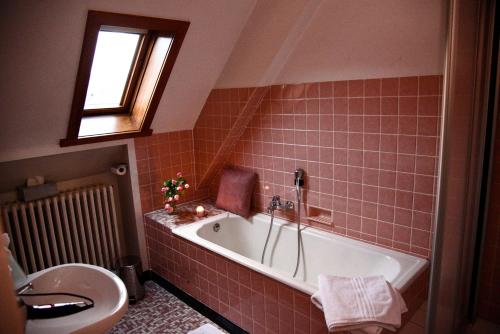 ein Bad mit einer Badewanne und einem WC in der Unterkunft Hôtel Deybach in Munster