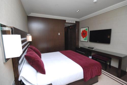 a bedroom with a bed and a desk and a television at Hotel Los Peñascales - Adults Only in Las Rozas de Madrid