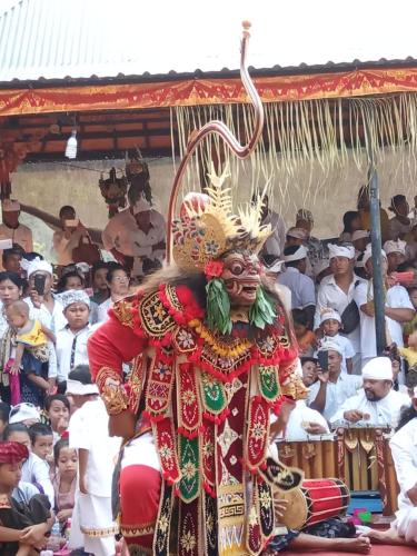 a person wearing a mask and a crowd of people at The Lumbung Tejakula in Tejakula