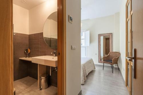 łazienka z umywalką, łóżkiem i lustrem w obiekcie Apartamento con encanto en el Barrio de Santa Cruz w Sewilli