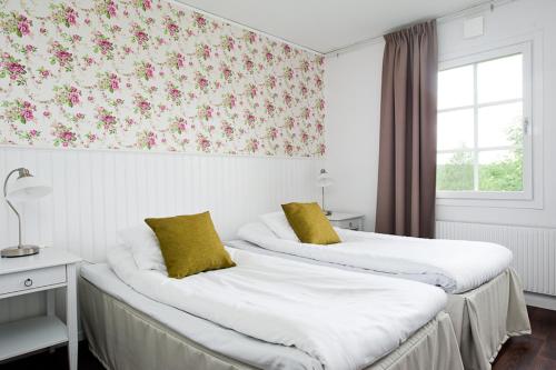 2 Betten in einem Hotelzimmer mit Blumentapete in der Unterkunft Gästisbacken in Alfta