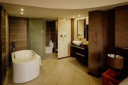 a bathroom with a tub and a sink and a toilet at SG Premium Resort in Arusha