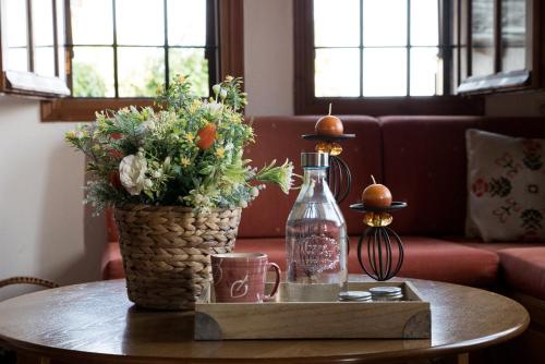 a table with a vase of flowers and a bottle on it at Pelion House with Wonderful View in Vizitsa