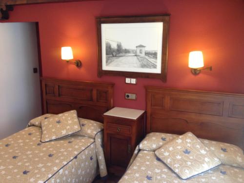 a bedroom with two beds and a picture on the wall at Hospedería Ana Pilar in Porcuna