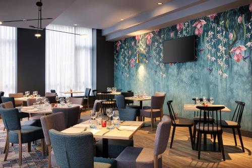 a restaurant with tables and chairs and a tv on a wall at Leonardo Hotel London Croydon in Croydon